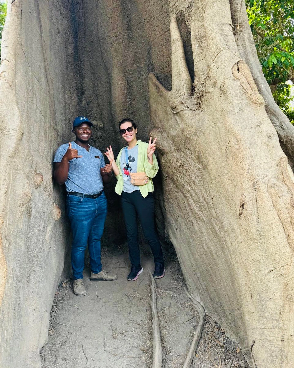 Gambia​ View Tours - Tourism services - A man and a woman pose together while standing inside the hollow trunk of a massive, ancient tree.