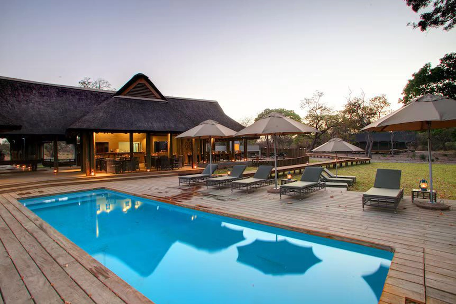 Gambia​ View Tours - Tourism services - Fathala lounge chairs under a large patio umbrella and a pool